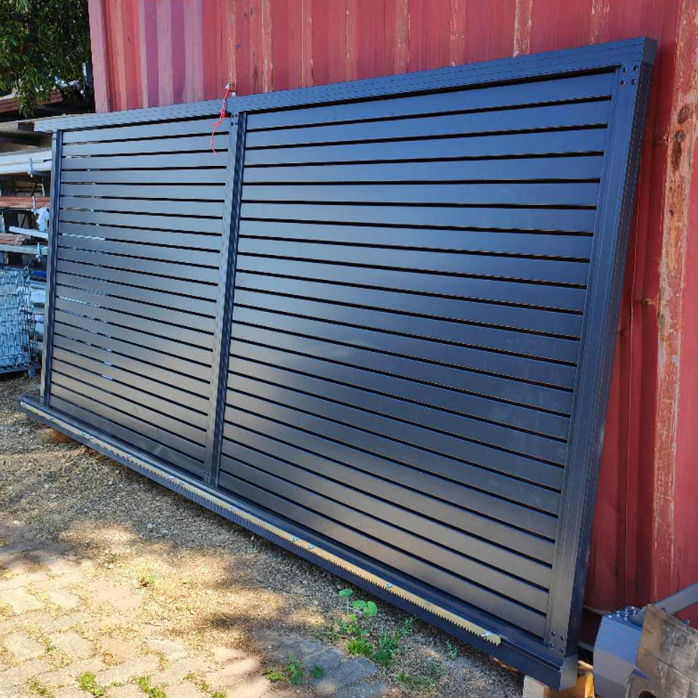 Large metal gate leaning against a red shipping container on a sunny day.